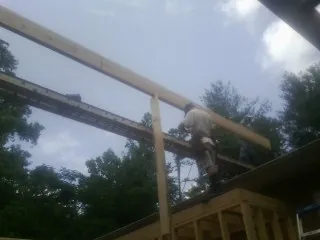Carpenter setting a ridge beam over a new addition frame — Ice Dam Removal by Roofing Brothers in Muir