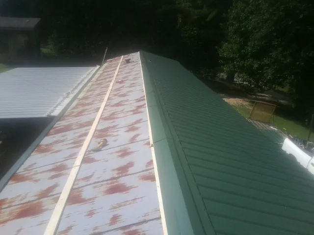 Old rusted panels beside newly installed green metal roofing — Wind Damage Roof Repair by Roofing Brothers in Muir