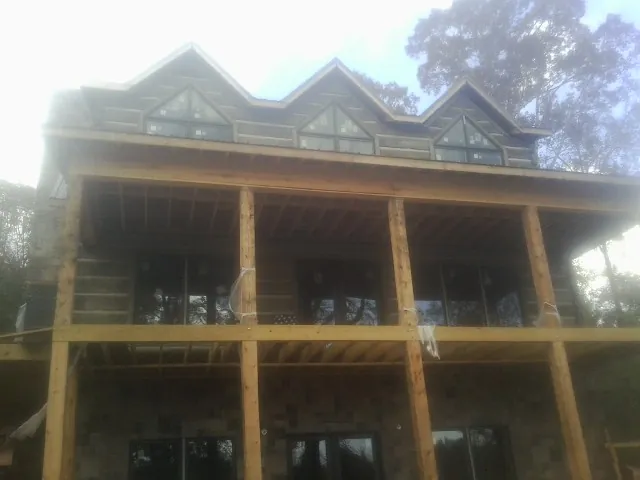 Dormers and porch framing on a large log home under construction — Roof Coating work by our crew in Muir