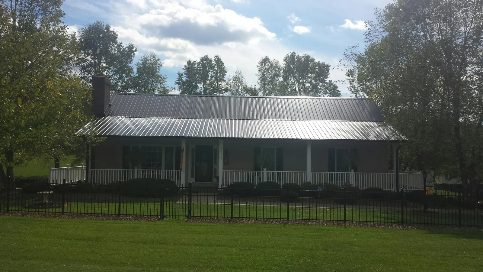 Gray metal roof on a brick ranch with a full width front porch — Gutter Guard Installation work by our crew in Muir
