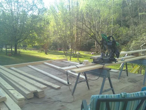 Miter saw and framing lumber on a deck under construction in Muir