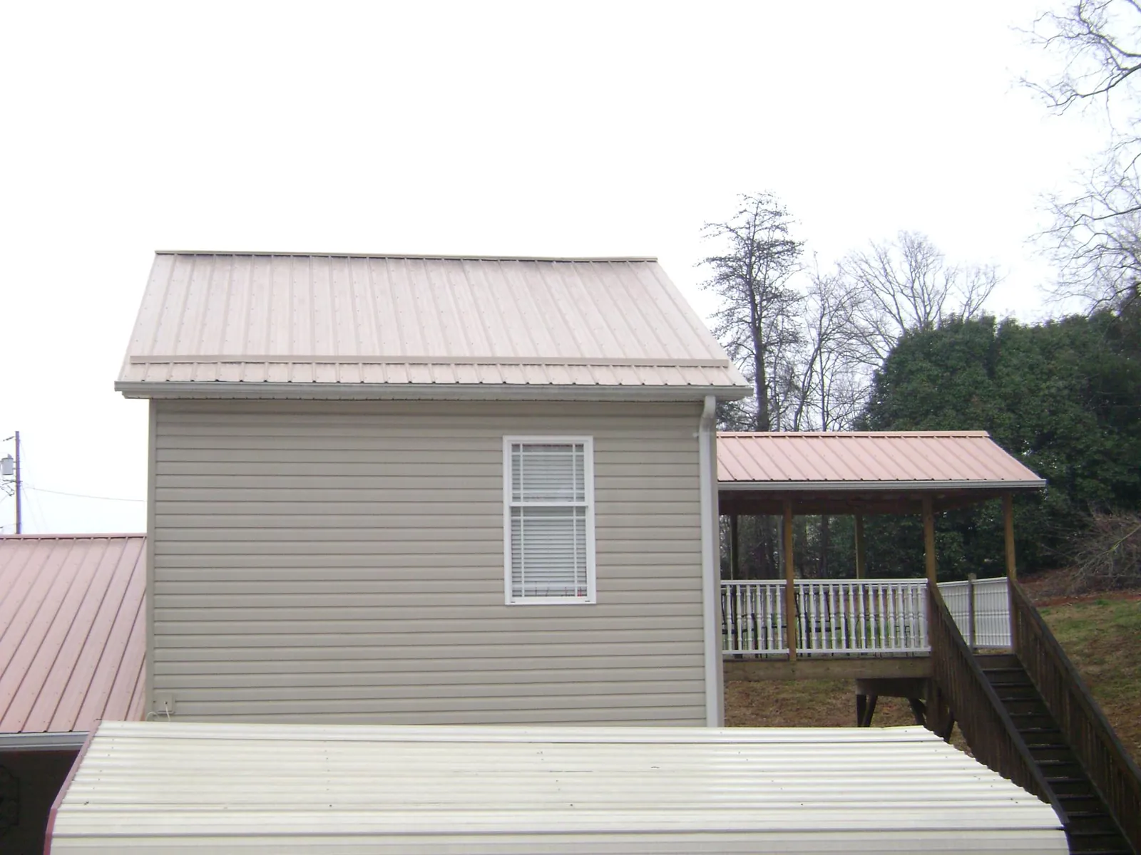 Tan metal roofs on a two story addition and attached porch, from a Roof Replacement job in Muir