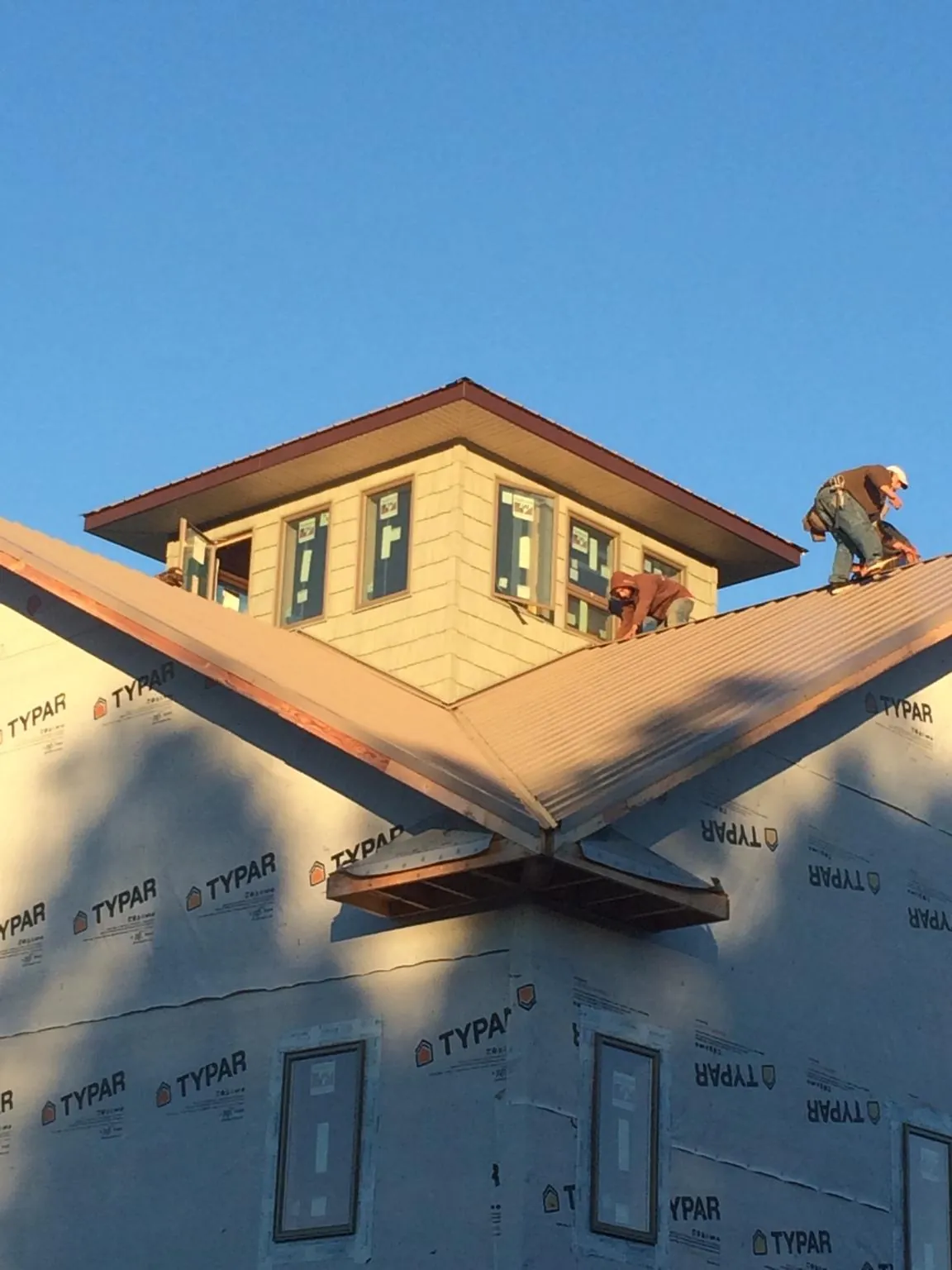 Roofers working around a rooftop cupola on a new metal roof at sunset — Roof Waterproofing in Muir by Roofing Brothers